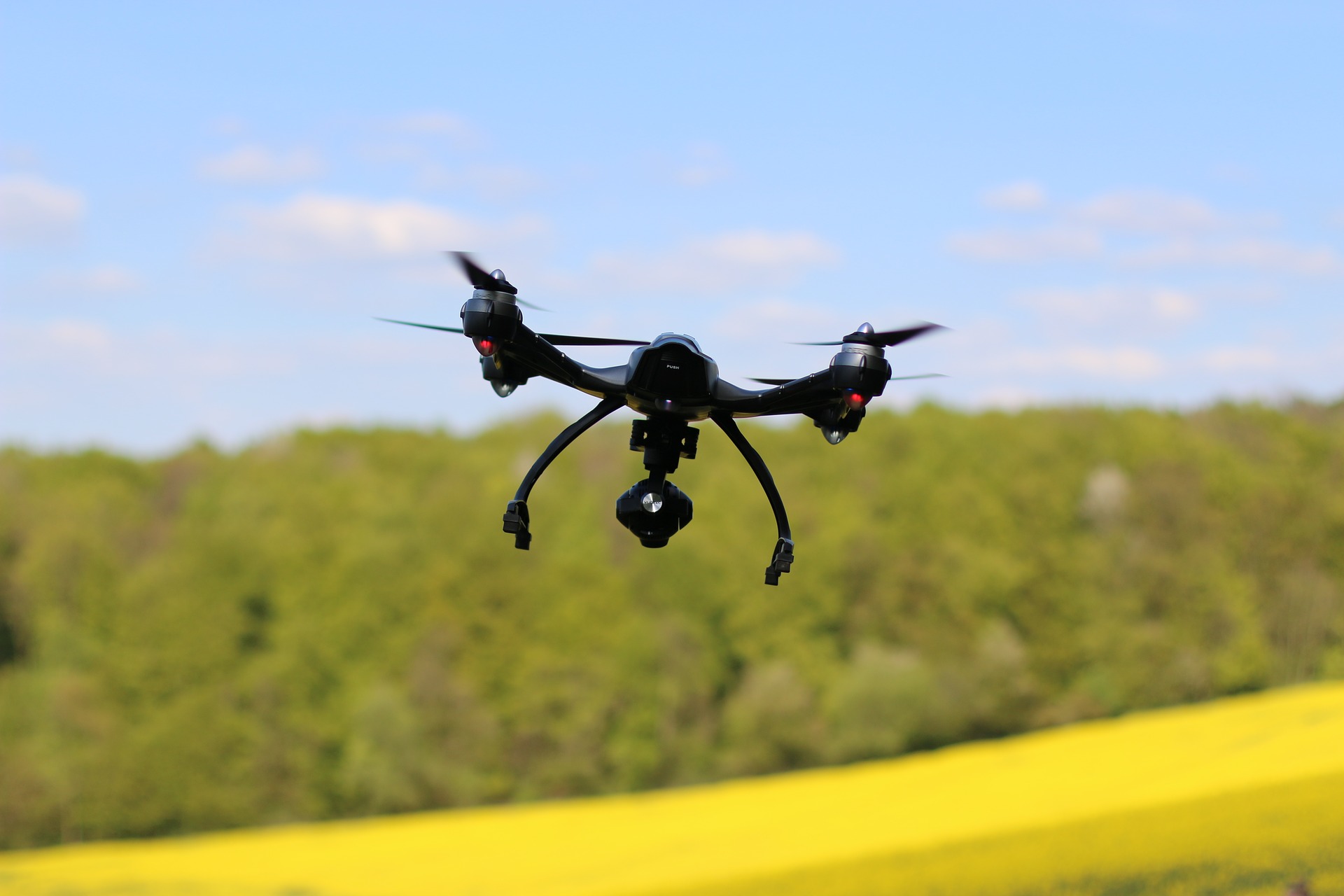 Fliegende Drohne über einem Rapsfeld.